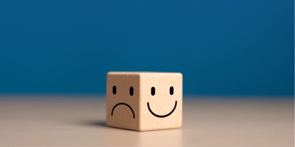Wooden die with frowning face and smiling face